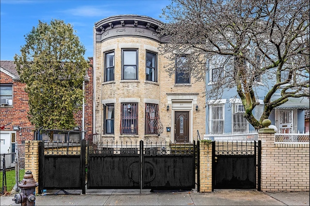 view of front of home with a gate, brick siding, and a fenced front yard