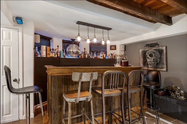 bar with tile patterned floors, beamed ceiling, and wet bar