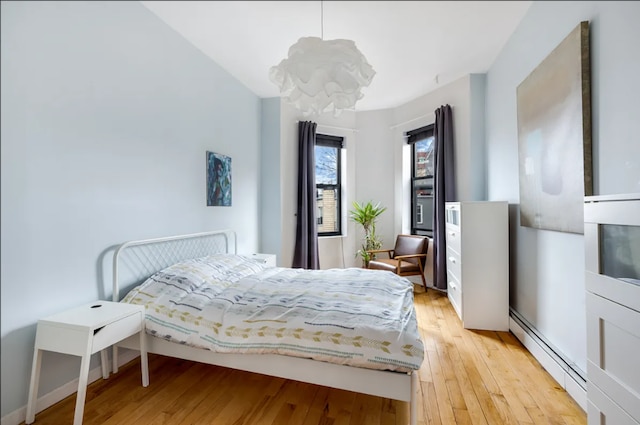bedroom with baseboard heating and light wood-style floors