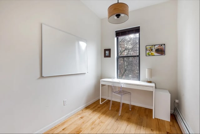 office area with a baseboard heating unit, hardwood / wood-style floors, and baseboards