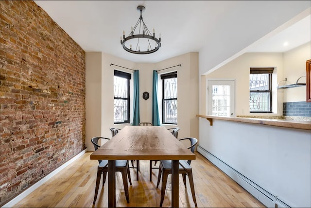 dining room with an inviting chandelier, a baseboard radiator, light wood-style floors, and a wealth of natural light