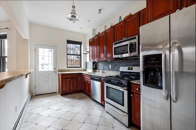 kitchen with reddish brown cabinets, appliances with stainless steel finishes, baseboard heating, backsplash, and a sink