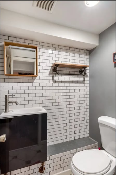 full bathroom featuring tiled shower, backsplash, toilet, vanity, and visible vents