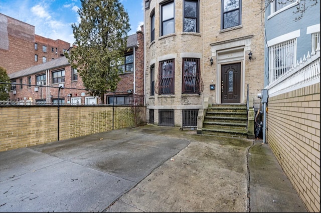 doorway to property featuring brick siding and fence