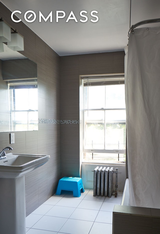 660 Macon St, New York City, NY 11233 - bathroom with radiator heating unit, tile patterned flooring, healthy amount of natural light, and tile walls