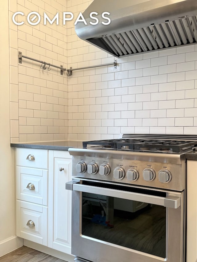 kitchen with gas range, dark countertops, wood finished floors, baseboards, and extractor fan