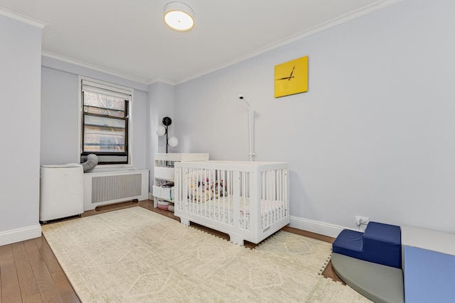333 E 34th St Unit 2M, New York City, NY 10016 - bedroom featuring radiator heating unit, crown molding, baseboards, and wood finished floors