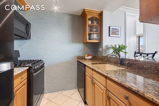 kitchen featuring a sink, glass insert cabinets, stone counters, and black appliances