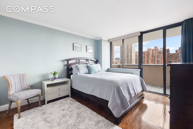 bedroom featuring crown molding, baseboards, a city view, and hardwood / wood-style flooring