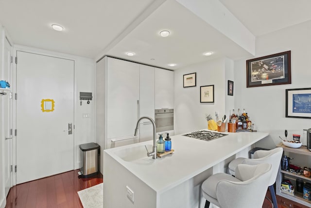 5-19 Borden Ave Unit 1-C, New York City, NY 11101 - kitchen with a sink, a kitchen bar, stainless steel appliances, dark wood finished floors, and light countertops