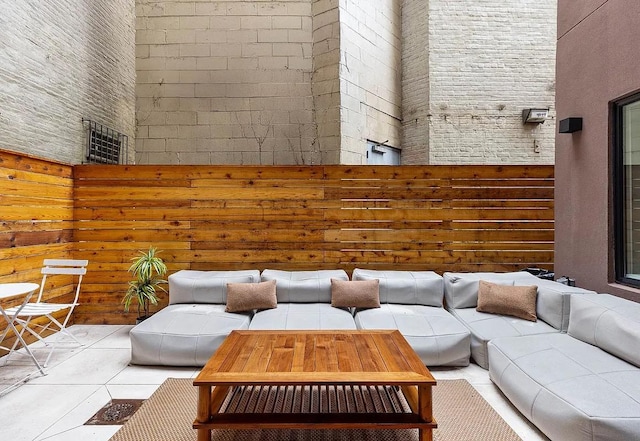 interior space featuring light tile patterned flooring, a towering ceiling, and wooden walls