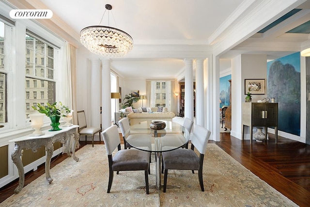 dining room featuring ornamental molding, decorative columns, wood finished floors, baseboards, and a chandelier
