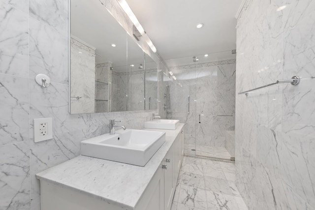 full bath featuring a marble finish shower, double vanity, a sink, and tile walls