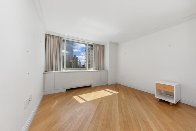 unfurnished room featuring light wood-style flooring, baseboards, and ornamental molding