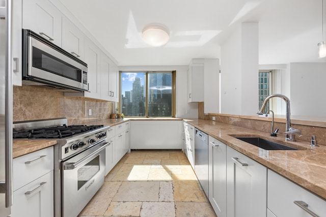 kitchen with a sink, white cabinetry, stone tile floors, stainless steel appliances, and backsplash