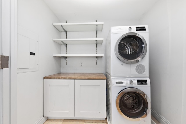 laundry room featuring stacked washer / dryer and baseboards