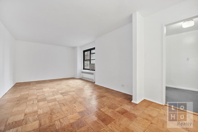 spare room with baseboards and radiator