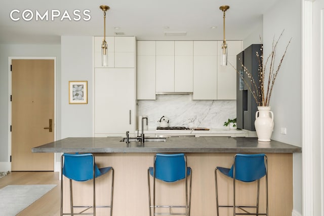 438 E 12th St Unit 6J, New York City, NY 10009 - kitchen with a sink, a kitchen breakfast bar, tasteful backsplash, hanging light fixtures, and wood finished floors