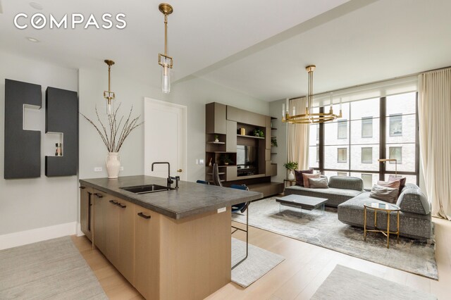 438 E 12th St Unit 6J, New York City, NY 10009 - kitchen featuring a sink, dark countertops, a peninsula, a chandelier, and light wood-type flooring