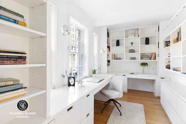 office space with built in desk and light wood-type flooring