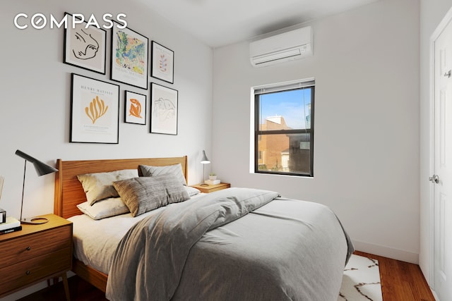 34-57 9th St, New York City, NY 11106 - bedroom featuring a wall mounted air conditioner and wood finished floors