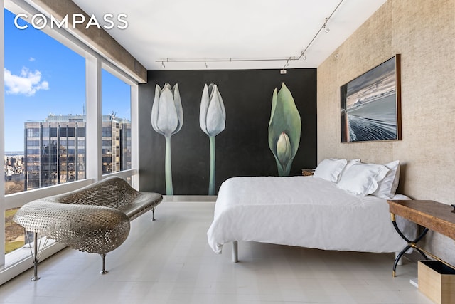 bedroom featuring rail lighting and a view of city