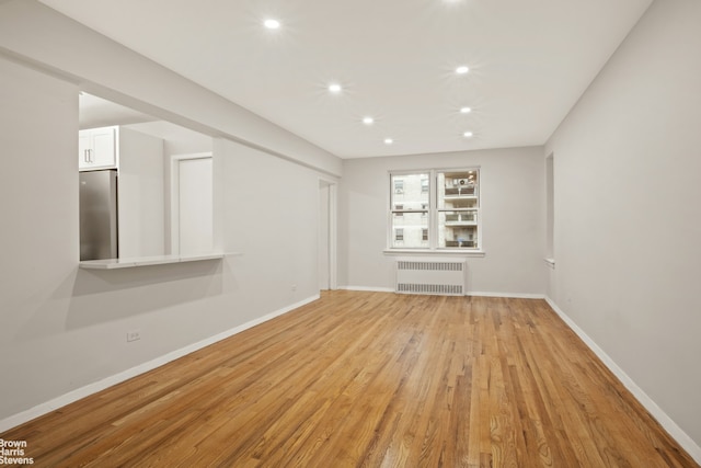 unfurnished living room with radiator heating unit, recessed lighting, light wood-style flooring, and baseboards