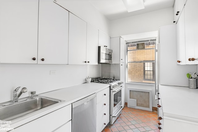 kitchen with a sink, light tile patterned floors, light countertops, white cabinets, and appliances with stainless steel finishes