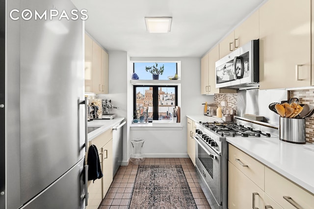 135 W 70th St Unit 8A, New York City, NY 10023 - kitchen featuring stainless steel appliances, tasteful backsplash, light countertops, cream cabinets, and baseboards