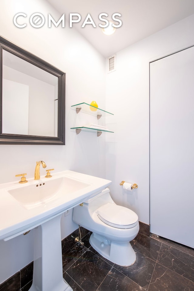 bathroom with marble finish flooring and toilet