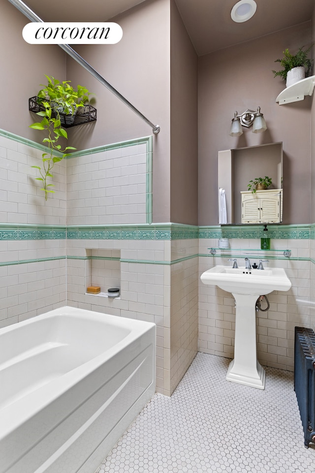 full bath featuring tile walls, radiator heating unit, a bath, and wainscoting