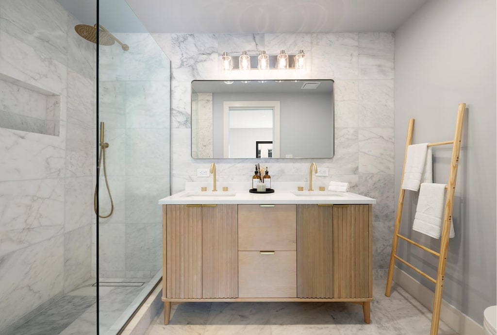 bathroom featuring tile walls, a marble finish shower, and a sink