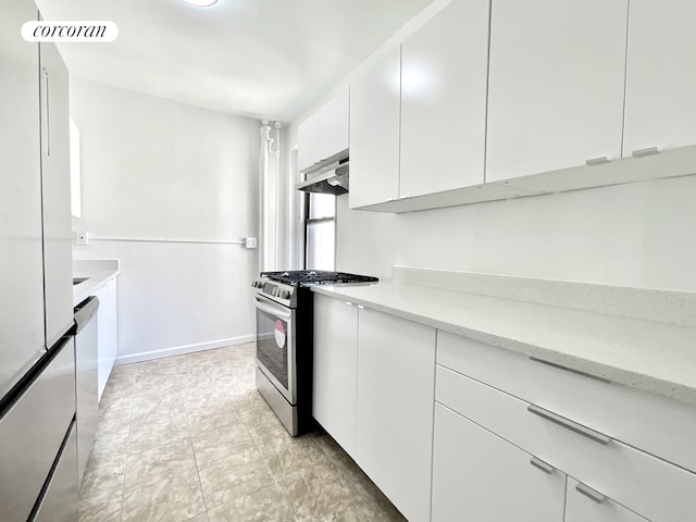 148-09 Northern Blvd Unit 6L, New York City, NY 11354 - kitchen featuring stainless steel gas range oven, under cabinet range hood, white cabinets, light stone counters, and freestanding refrigerator