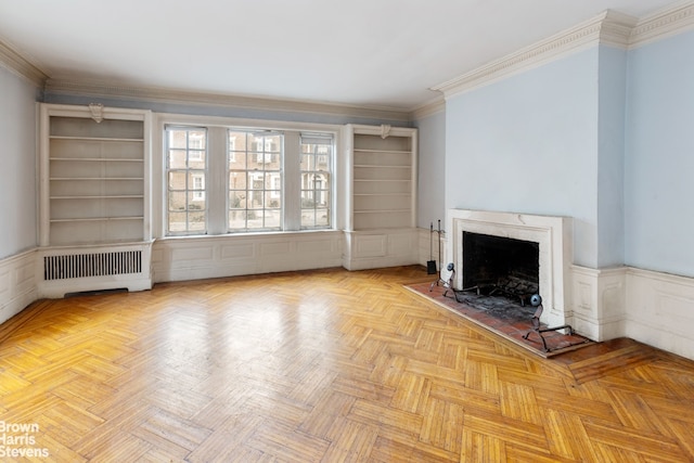 unfurnished living room featuring radiator, a wainscoted wall, a premium fireplace, and ornamental molding