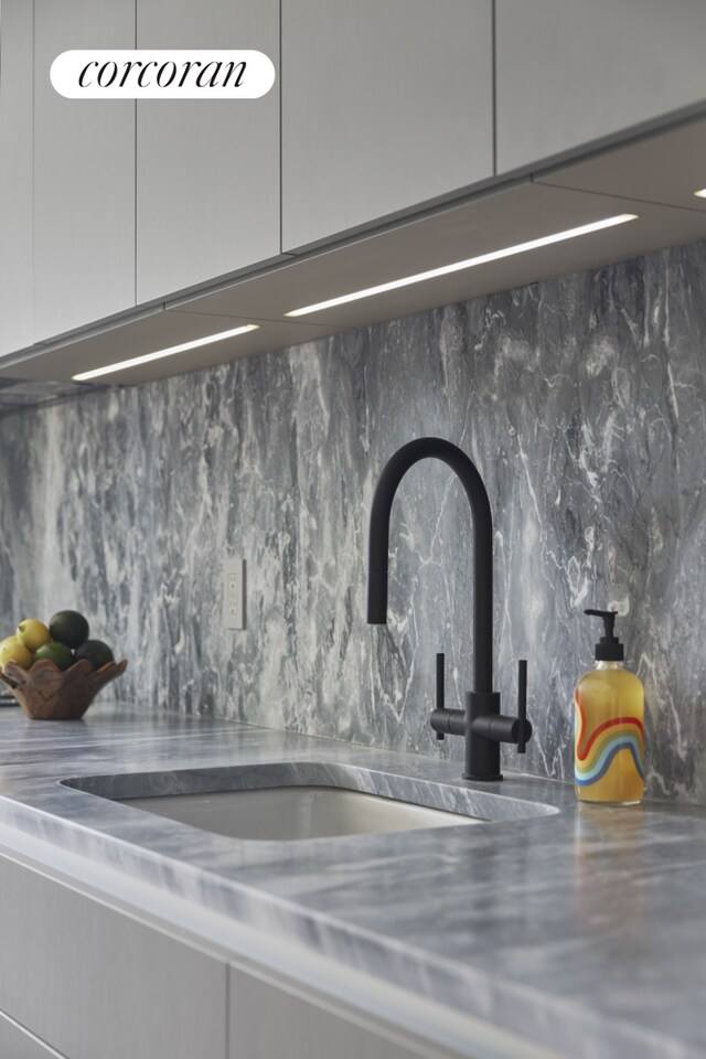 details with decorative backsplash, a sink, and stainless steel counters
