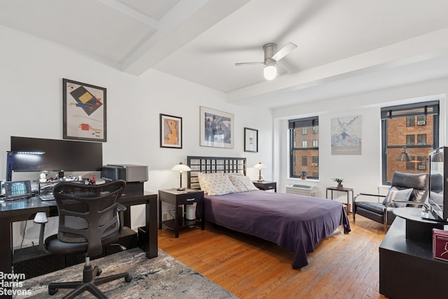 bedroom featuring wood finished floors, beamed ceiling, and a desk