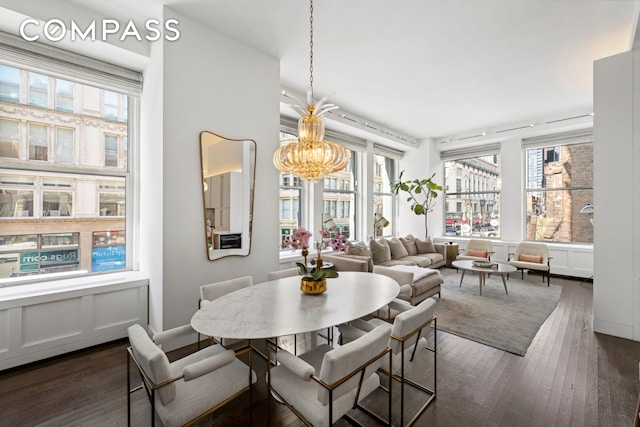 dining room with dark wood-style flooring, a chandelier, and baseboards