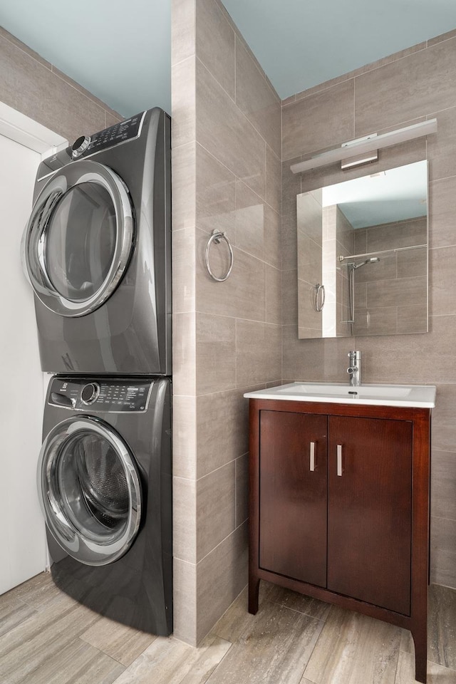 157 W 78th St Unit 6/5S, New York City, NY 10024 - laundry area with tile walls, a sink, laundry area, light wood-type flooring, and stacked washer and dryer