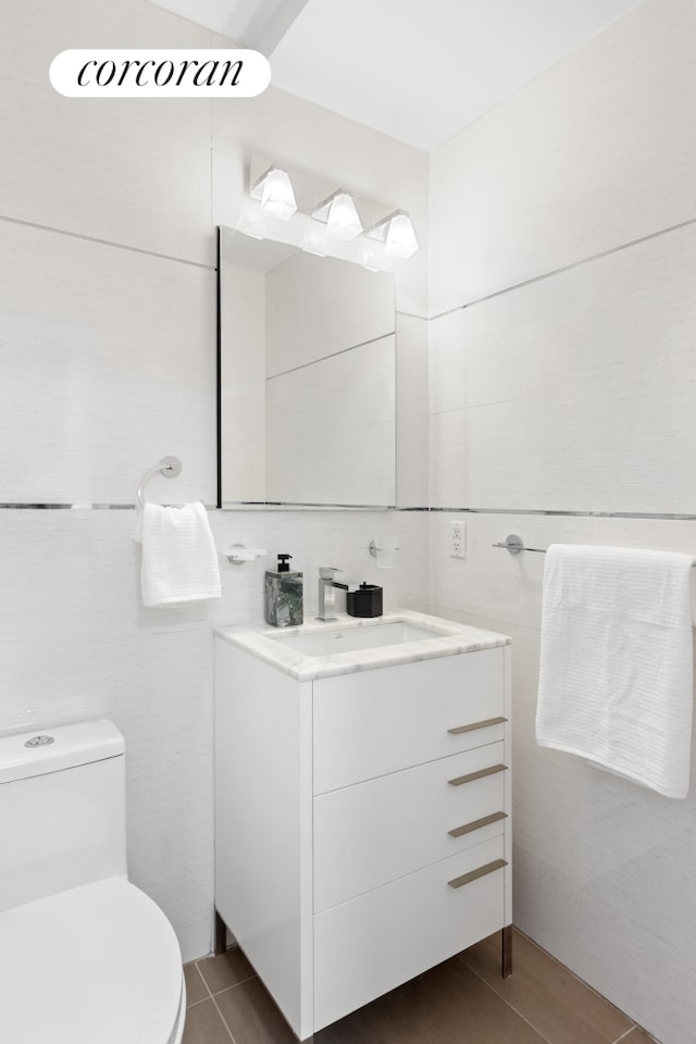 half bathroom with toilet, tile walls, and vanity