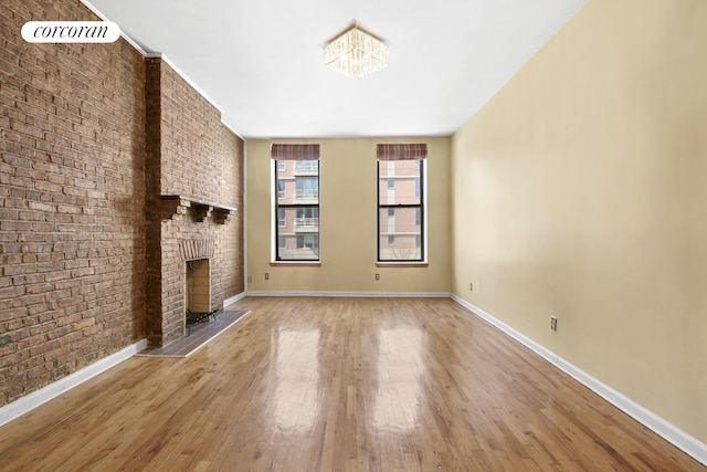 101 4th Ave Unit 2R, New York City, NY 11217 - unfurnished living room featuring hardwood / wood-style floors, baseboards, brick wall, and a brick fireplace