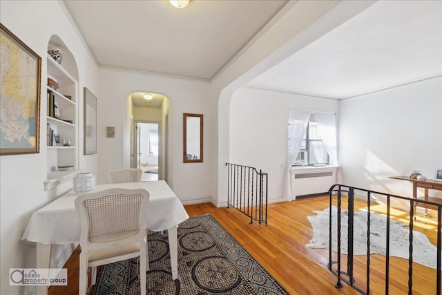 45 Park Ter W Unit 6E, New York City, NY 10034 - dining space featuring radiator heating unit, arched walkways, wood finished floors, and ornamental molding