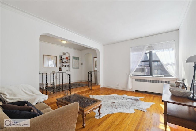 45 Park Ter W Unit 6E, New York City, NY 10034 - living room with radiator heating unit, arched walkways, ornamental molding, and wood finished floors