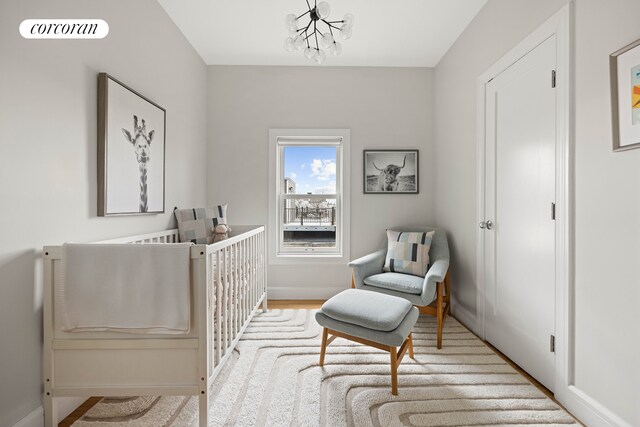 bedroom featuring a crib, a chandelier, and baseboards