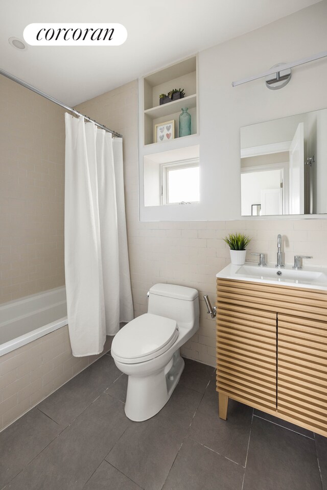 bathroom with tiled shower / bath combo, tile patterned floors, tile walls, toilet, and vanity