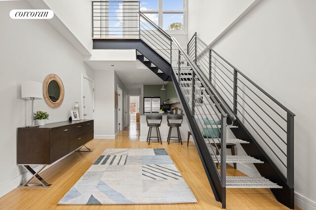 entrance foyer featuring baseboards, wood finished floors, a wealth of natural light, and a towering ceiling