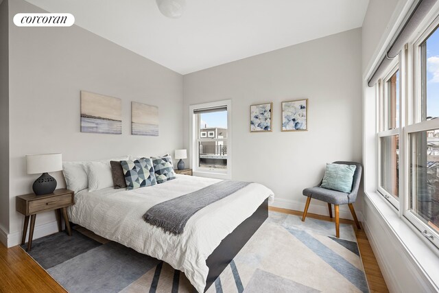 bedroom with baseboards, visible vents, wood finished floors, and multiple windows