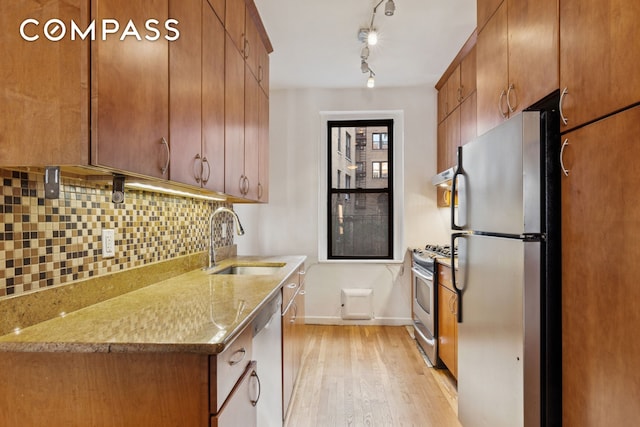 115 Cabrini Blvd Unit B51, New York City, NY 10033 - kitchen with appliances with stainless steel finishes, a sink, light wood-style flooring, tasteful backsplash, and ventilation hood