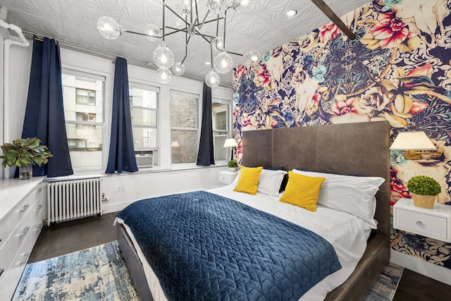 bedroom with radiator, a notable chandelier, wood finished floors, and an ornate ceiling