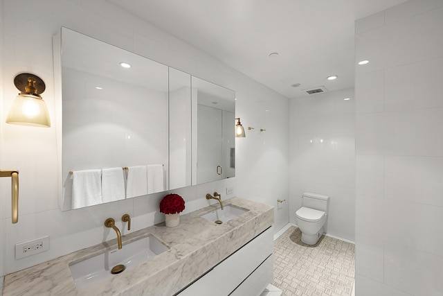 bathroom featuring visible vents, a sink, toilet, and double vanity