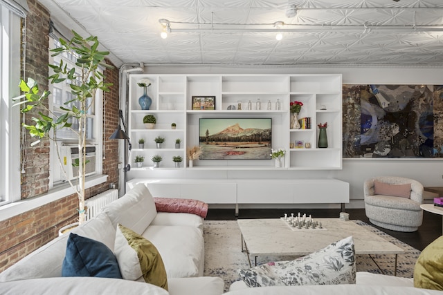 living room featuring an ornate ceiling and brick wall